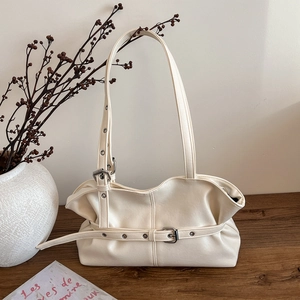 Sac bandoulière vintage blanc crème en cuir souple avec détail de boucle sur une table