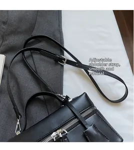 Détail de la bandoulière réglable et du double zip argenté sur le sac en cuir noir