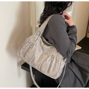 Detail of grey soft leather tote bag with functional silver zippers and wide shoulder strap