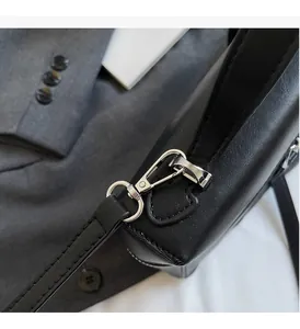 Detail of silver metal clasp and fine stitching on a black leather handbag strap