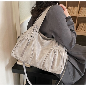 Detail of grey vintage textured tote bag featuring multiple pockets and silver hardware