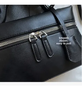 Detail of smooth silver double zippers on textured black leather shoulder bag