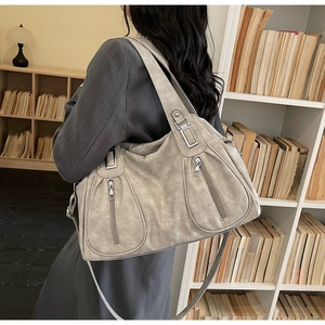 Detail view of large taupe tote bag with vertical zippers and vintage leather texture