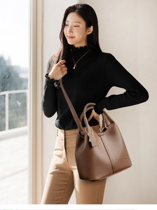 Gros plan du sac à main en cuir marron avec motif litchi, logo embossé et couture fine