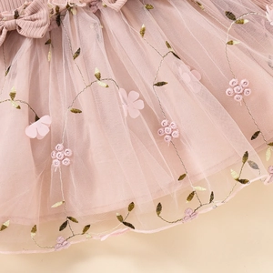 Detail of pink mesh dress featuring 3D floral embroidery and delicate bow accent
