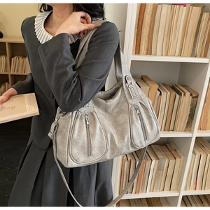 Close-up of metallic silver tote bag with multiple zip pockets and pleated detail