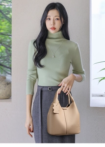 Détail du sac seau en cuir beige grainé avec logo kangourou embossé et étiquette latérale
