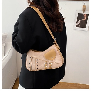 Detail view of khaki saddle bag with metallic grommets and buckles on a model