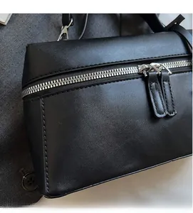 Détail du sac carré noir avec fermetures éclair argentées et texture en cuir délicat