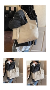 Detail of minimalist cream tote bag showing pebble leather texture and small matching pouch