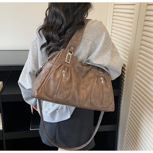 Detail of vintage brown shoulder bag showing soft PU leather texture and vertical zipper pockets