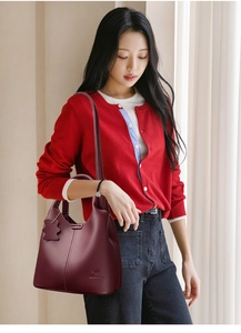 Détail du sac cabas en cuir bordeaux à texture litchi porté par une femme mannequin