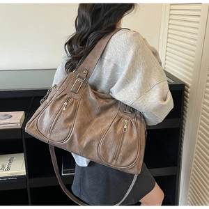 Brown vintage faux leather tote bag with dual front zipper pockets shown on a model