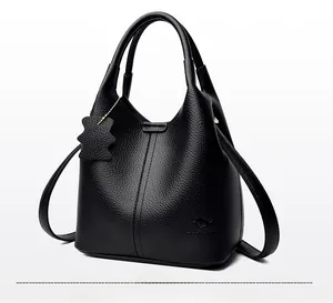 Vue latérale du sac seau noir en cuir grainé avec deux poignées et logo de la marque