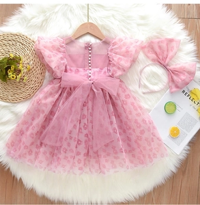 Détail de robe princesse en tulle rose à fleurs avec grand nœud et boutons perles