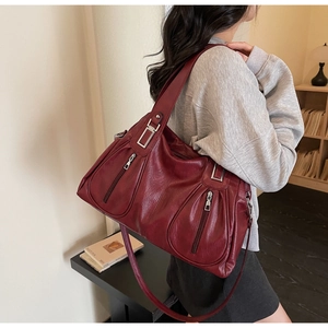 Detailed close-up of burgundy tote bag with litchi grain texture and metallic zippers