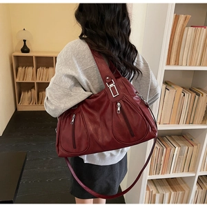 Macro detail of wine red leather tote bag with silver square hardware and vertical zippers
