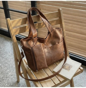 Detail of vintage brown PU leather tote bag with small zipper pouch on a wooden chair