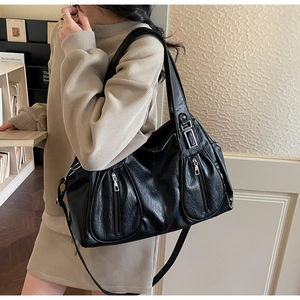 Close-up of black leather tote bag featuring two decorative front zippers and silver hardware