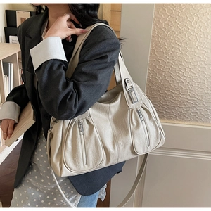 Detail of cream white PU leather tote bag with silver zippers and dual strap design