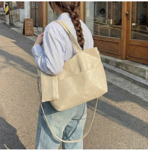 Close-up of a large beige soft PU leather tote bag with a matching small hanging pouch