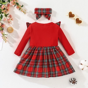 Flat lay of baby girl Christmas dress with red ribbed top and plaid skirt and headband