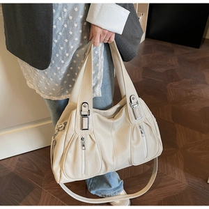 Detail showing cream leather tote with silver zippers and wide shoulder strap