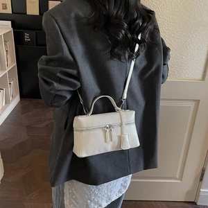 Détail du sac à main rectangulaire en cuir blanc cassé avec double zip et poignée supérieure