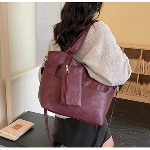 Detail view of large burgundy tote bag in soft PU leather with matching mini pouch charm