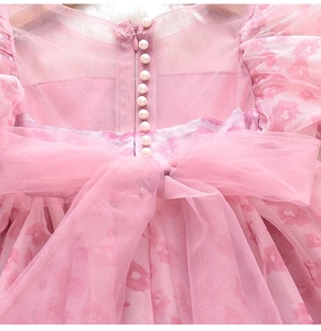 Détail de robe fleurie rose avec fermeture éclair, boutons perles et nœud en tulle