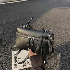 Détail d'un sac carré noir mat avec doubles fermetures éclair argentées et bandoulière