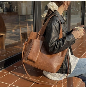 Detail of vintage brown PU leather tote bag with matching small pouch on city steps
