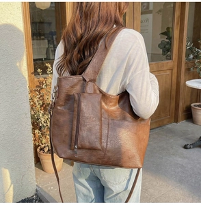 Macro detail of dark brown vintage PU leather tote bag with functional hanging pouch