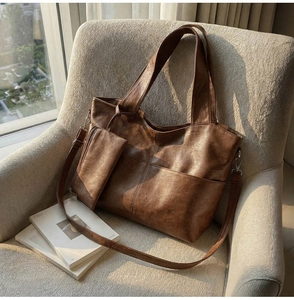 Detailed view of brown vintage PU leather tote bag with a small matching zip pouch