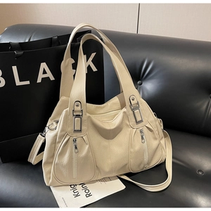 Detailed close-up of cream leather tote bag with silver zippers and lychee grain texture