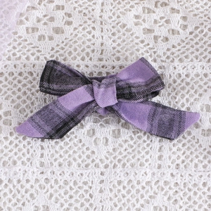 Macro view of purple plaid fabric bow on white lace background for holiday dress decoration