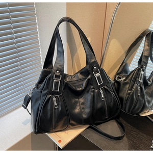 Detail of black leather tote bag with silver zippers and adjustable shoulder strap