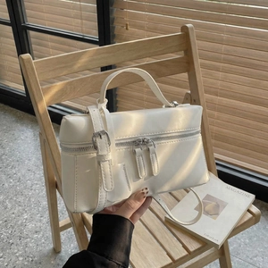 Gros plan d'un sac à main carré en cuir blanc avec doubles fermetures éclair et finition lisse