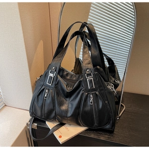 Detail of black tote bag featuring wrinkled PU leather texture and silver hardware zippers