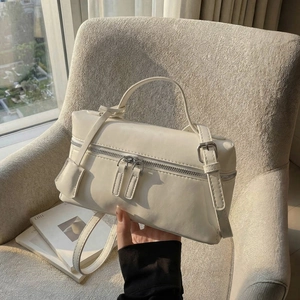 Vue détaillée d'un sac à main carré blanc avec double fermeture éclair sur un fauteuil