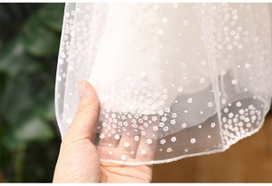 Detailed view of white floral embroidery on soft mesh fabric of girl's princess dress
