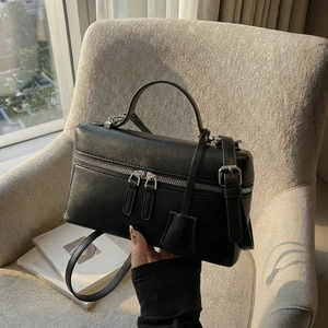 Détails d'un sac à main carré noir avec ferrures argentées et cuir synthétique lisse