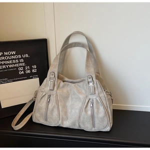 Close-up of matte grey tote bag featuring vertical zippers and metallic buckle details