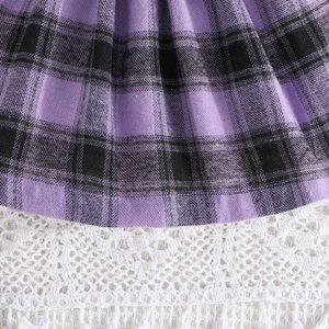 Detail of purple plaid dress featuring pleated fabric and white floral lace hem