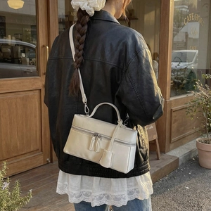 Détail du sac rectangulaire blanc cassé avec doubles zips et étiquette en cuir