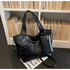 Macro shot of black faux leather tote bag with pebble texture and matching small pouch