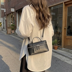 Détail d'un sac à main carré en cuir noir structuré avec double fermeture éclair