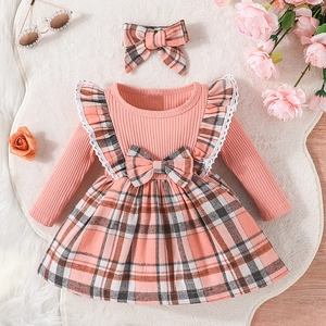 Flat lay of pink knit toddler dress with plaid skirt and matching bow headband