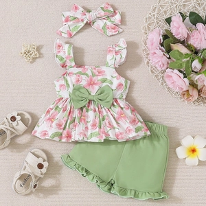 Flat lay of baby girl summer floral camisole top, ruffled shorts, and matching headband