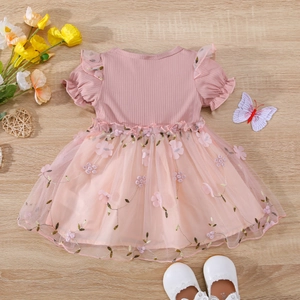 Detail of pink baby dress showing floral embroidery, mesh tulle, and 3D flower accents